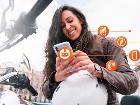Vrouwelijke motorrijder staat naast haar motor en opent een app op haar smartphone